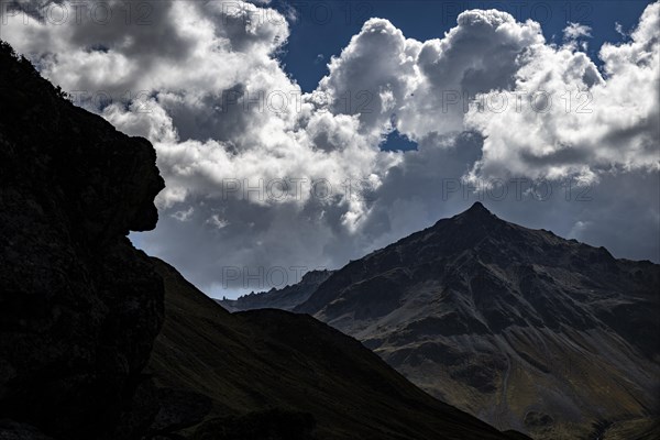 Striking peak of Piz de Agnel with cloudy sky against the light