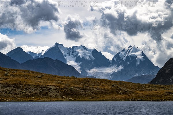 Mountain lake Lej Suvretta with Bernina group and Engadine mountains with cloudy sky