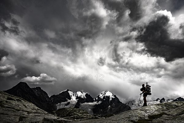 Climbers in front of summit of Bernina Group with dramatic clouds