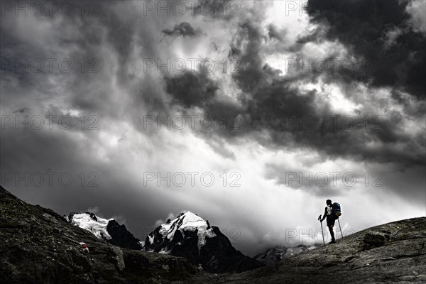 Climbers in front of summit of Bernina Group with dramatic clouds