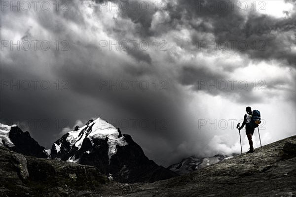 Climbers in front of summit of Bernina Group with dramatic clouds