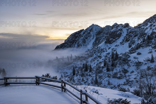 Mountain slope with snow at sunrise with clouds and clear sky and high fog
