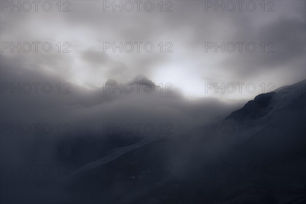 Summit of Piz Rosegg with Rosegg glacier and dramatic clouds at blue hour