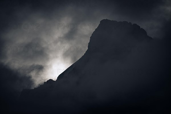 Peak of Piz Rosegg in dramatic clouds at blue hour