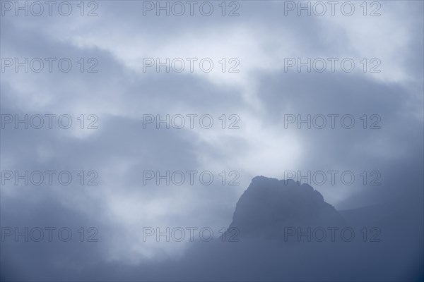 Peak of Piz Rosegg in dramatic clouds at blue hour