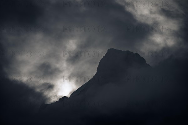 Peak of Piz Rosegg in dramatic clouds at blue hour