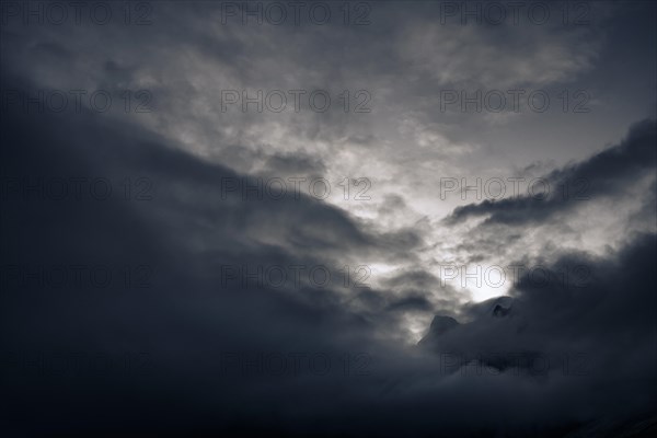 Peak of Piz Rosegg in dramatic clouds at blue hour