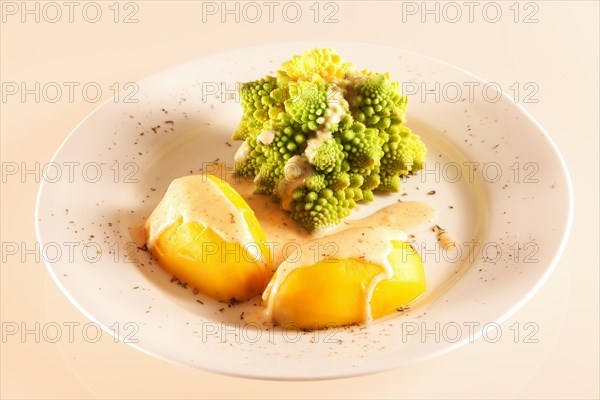 A portion of romanesco with boiled potatoes and cheese sauce