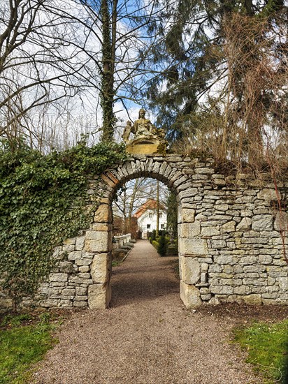 Sculpture on wall with gate to baroque garden