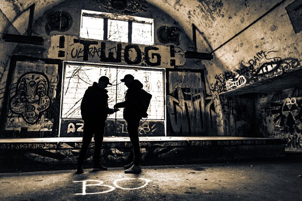 Two men as silhouette in bunker with graffiti walls