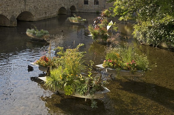 Zinc tubs in the shape of boats with flowering plants on the river Gera