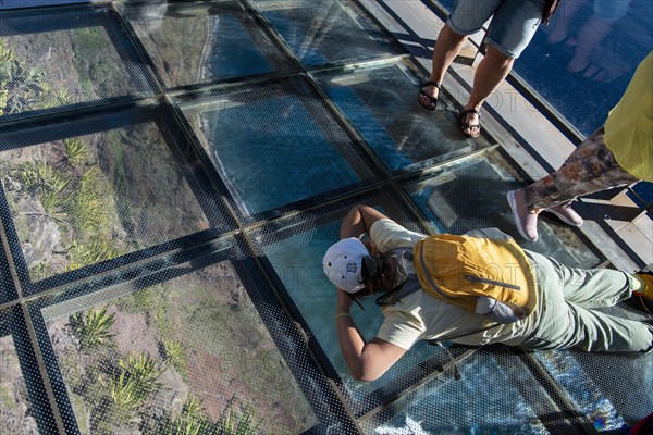 Tourist looks through the glass floor 580 metres into the depths