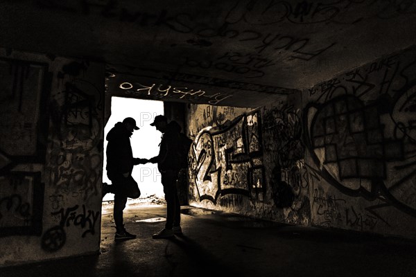 Two men as silhouette in bunker with graffiti walls