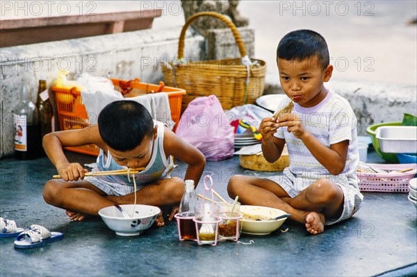 Boys eating noodle soup and chicken at the Wat Pho temple