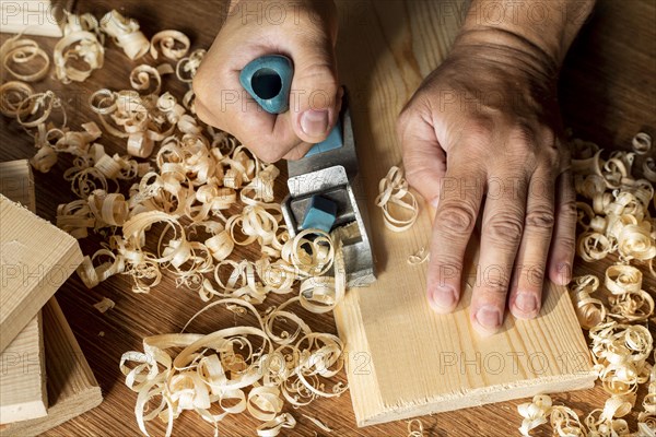 Carpenter working wood surrounded by sawdust