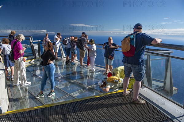 Tourists look at the view from the glass-bottom skywalk