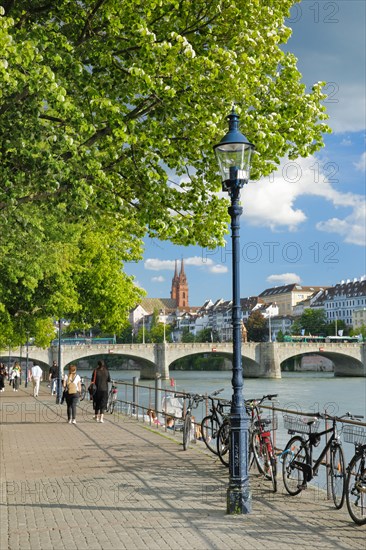 View from the banks of the Rhine along the river promenade to the old town of Basel with the Basel Cathedral