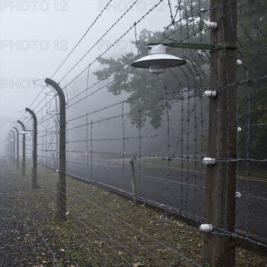 Reconstructed camp fence with crematorium in the fog at beech forest concentration camp