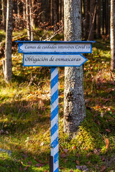 White-blue sign indicating which direction to go. Mask requirement or intensive care beds. Lettering in Spanish language