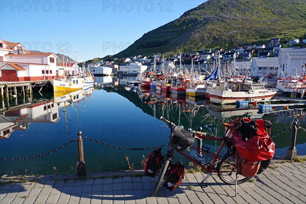 Bicycle in front of harbour with small fishing boats reflected in the calm water