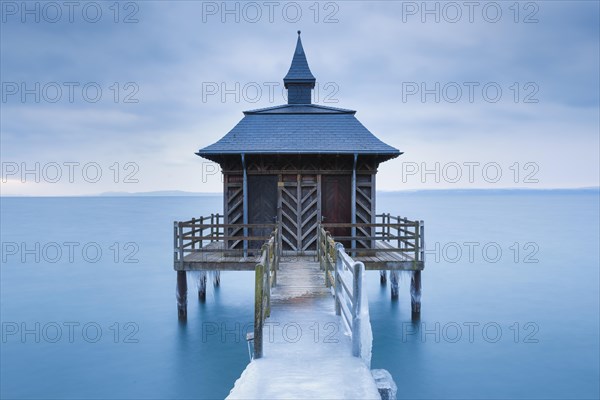 Iced wooden bathhouse at dawn on Lake Neuchatel in Gorgier