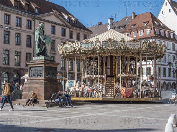 Statue de Johannes Gutenberg and next to him the children's museum carousel Merry go round Gutenberg at Place Gutenberg