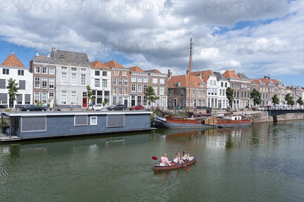 Canoe in front of historic house facades and houseboats at Londensekaai
