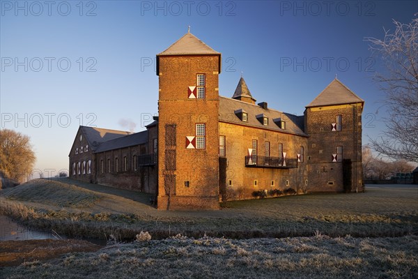 Water castle Haus Zelem with hoarfrost at sunrise