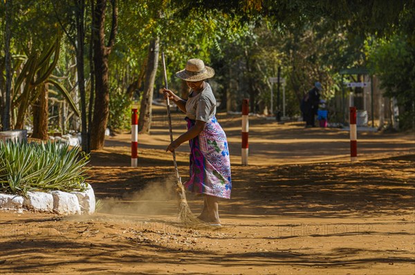 Woman cleaning the street with a broom