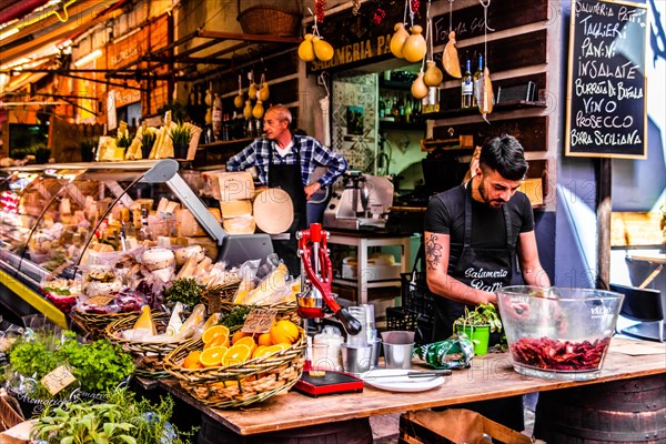 Ham and cheese stall at the historic fish market La pescheria with an abundance of colourful seafood