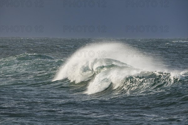 Big wave breaks in the open sea on the Breton coast near Brest