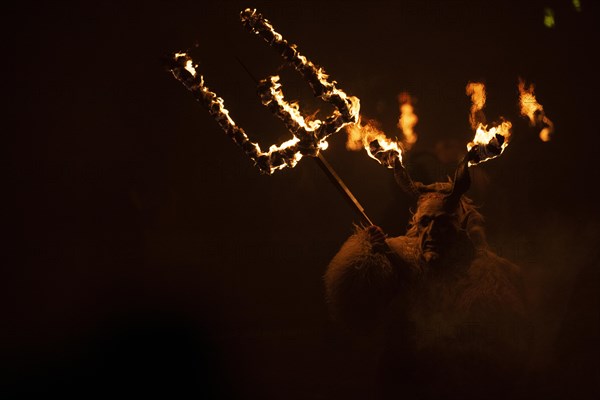 Klausen mask with burning horns and trident in the dark