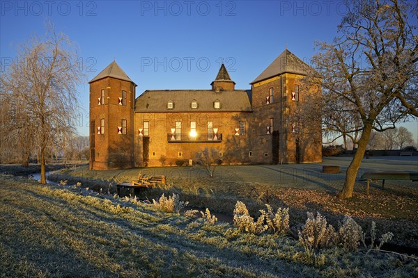 Water castle Haus Zelem with hoarfrost at sunrise