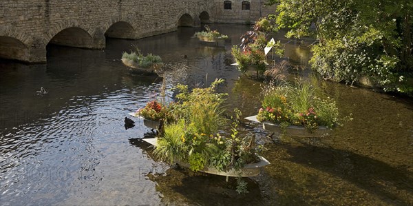 Zinc tubs in the shape of boats with flowering plants on the river Gera