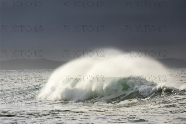 Big wave breaks in winter storm in open sea and dramatic light off north coast of Ireland