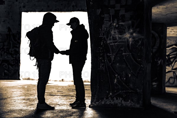 Two men as silhouette in bunker with graffiti walls