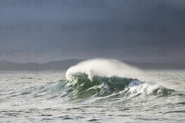 Big wave breaks in winter storm in open sea and dramatic light off north coast of Ireland