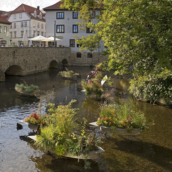 Zinc tubs in the shape of boats with flowering plants on the river Gera