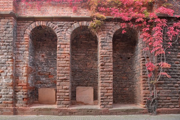 Three archways with clinker stones and stone wall with vines at the church