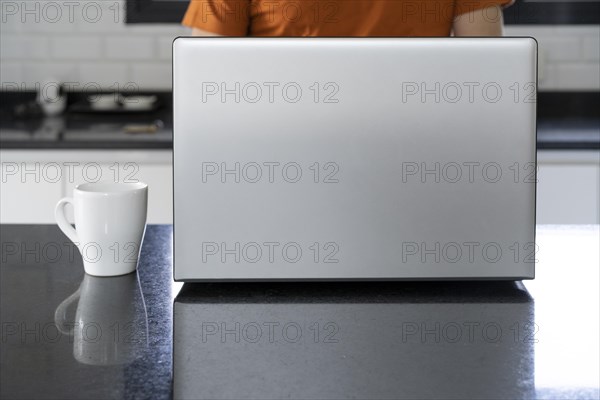 Laptop and cup of coffee on the kitchen island. Man working at home