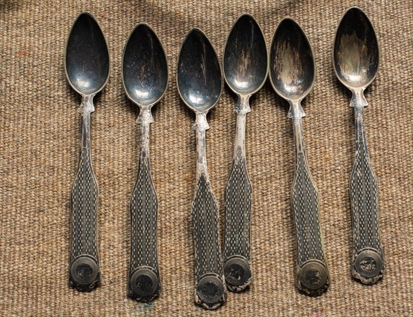 Stylish steel teaspoons on a textured background in display