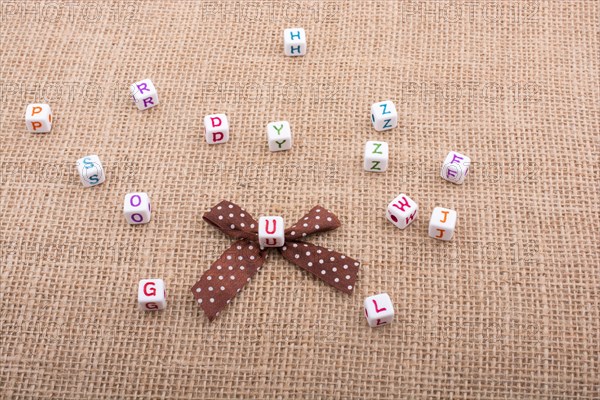 A ribbon and scattered dice-sized alphabet cubes on a textured surface in display