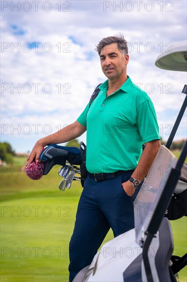 A professional golf player in a green polo shirt with the bag of clubs