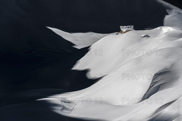 Mountain hut in deep snowy mountain landscape with light and shadow