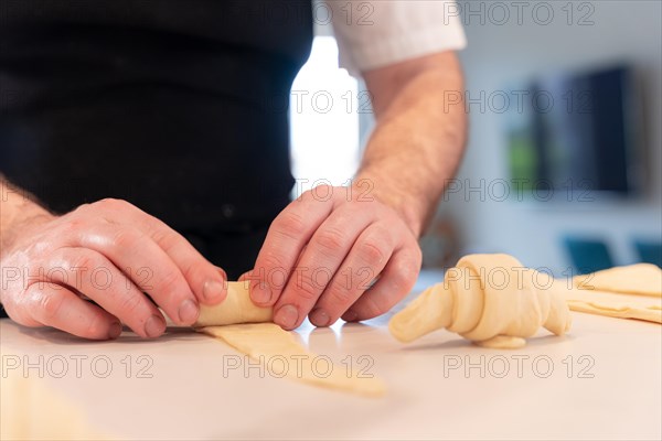 Hands of a man baking small croissants at home