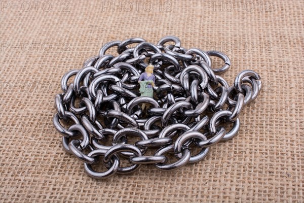 Woman figurine on steel chains on a textured surface on display