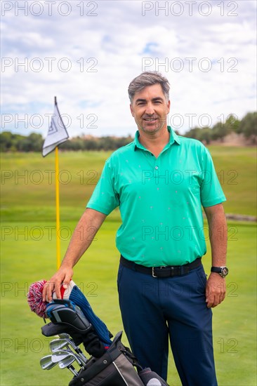 Portrait of a man playing golf along with the clubs on the green