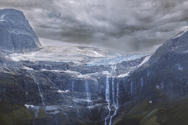 Water from a melting glacier in Norway runs down the rock faces