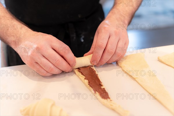 Hands of a man baking small chocolate croissants at home