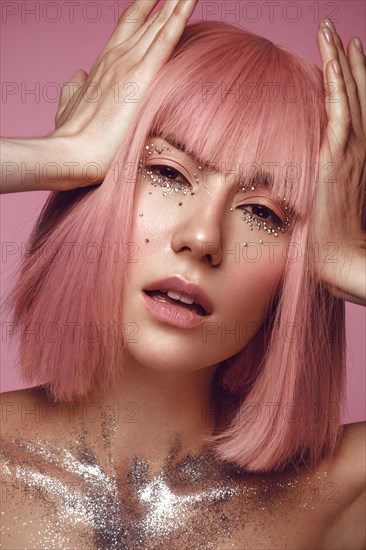 Beautiful woman in a pink wig and creative makeup with rhinestones. Beauty face. Photo taken in the studio